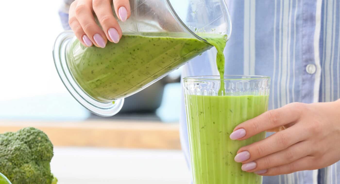  Kobieta nalewa zielony koktajl do szklanki