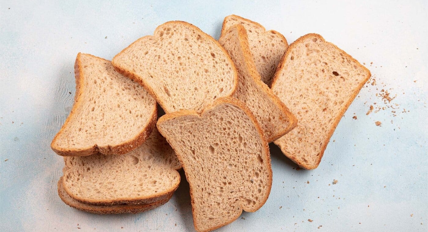 Leżące na szarym tle czerstwe kromki ciemnego chleba