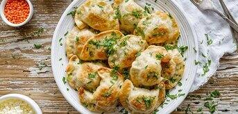 Pierogi na talerzu ze szczypiorkiem, białym serem i soczewicą - zdjęcie.