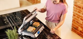 A woman skillfully prepares sandwiches on MultiGrill 9 Pro
