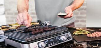 Mężczyzna przyprawiający kebabczety na grillu MultiGrill 9 Pro - zdjęcie.