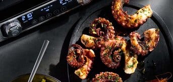 Obok grilla Braun znajduje się talerz grillowanych krewetek z ośmiornicą i salsą ananasową.