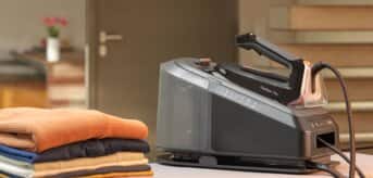 Żelazko z generatorem pary Braun CareStyle7Pro na desce do prasowania i wyprasowanymi ubraniami - zdjęcie.