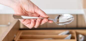 Dłoń wkładająca łyżkę do szuflady
