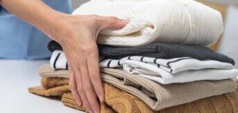 Ręce trzymające poskładane swetry