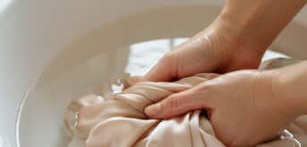 Ręczne pranie jedwabnej tkaniny w misce z wodą. - zdjęcie