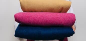 Kobieta trzymająca poskładane swetry z kaszmiru