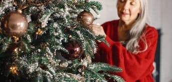 Kobieta w średnim wieku ubierająca choinkę - zdjęcie.