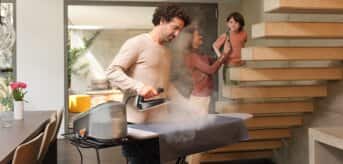 Uśmiechnięty mężczyzna prasuje używając generatora pary Braun CareStyle 7 Pro