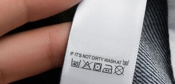 Ręka pokazująca metkę doszytą do jeansów z instrukcją prania