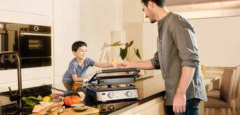 Braun MultiGrill 7 in use. Man with boy in kitchen.