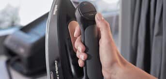 Osoba trzymająca żelazko z generatorem pary Braun CareStyle 7 Pro i wisząca spódnica - zdjęcie.