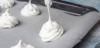 Wyciskanie masy bezowej na papier do pieczenia - zdjęcie.