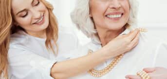 Dwie uśmiechnięte kobiety zakładające sznur pereł - zdjęcie.