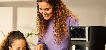 Matka i córka gotujące razem w kuchni przy użyciu Multifry 5 marki Braun. - zdjęcie