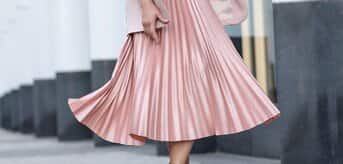 Kobieta w różowej plisowanej spódnicy i różowych sneakersach - zdjęcie.