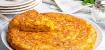 Omlet tortilla española jako wysoki placek z ziemniakami na talerzu - zdjęcie.