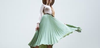 Kobieta w plisowanej długiej spódnicy i kapeluszu - tytułowa.