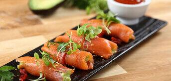 Dish with smoked salmon and avocado rolls with saseme seeds and goji berry sauce
