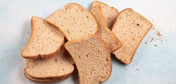 Leżące na szarym tle czerstwe kromki ciemnego chleba