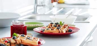 Osoba posypująca gofry na słodko - zdjęcie.