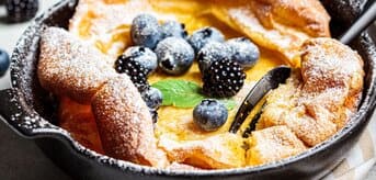 Omlet dutch baby w żaroodpornym naczyniu z cukrem pudrem i owocami - zdjęcie.