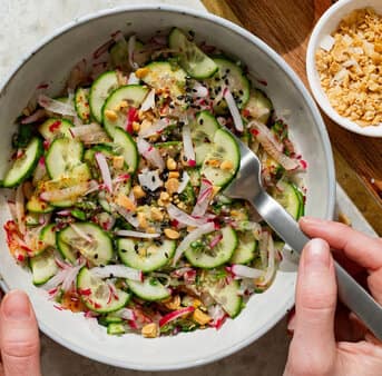 View from above of a white marble table with a bowl filled with fresh Thai cucumber salad.