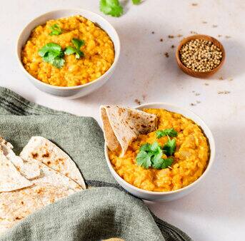 A delicious Indian lentil curry served with pita bread on a white plate.